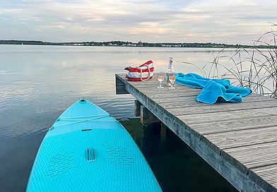 SUP-Board im Wasser neben Steg.