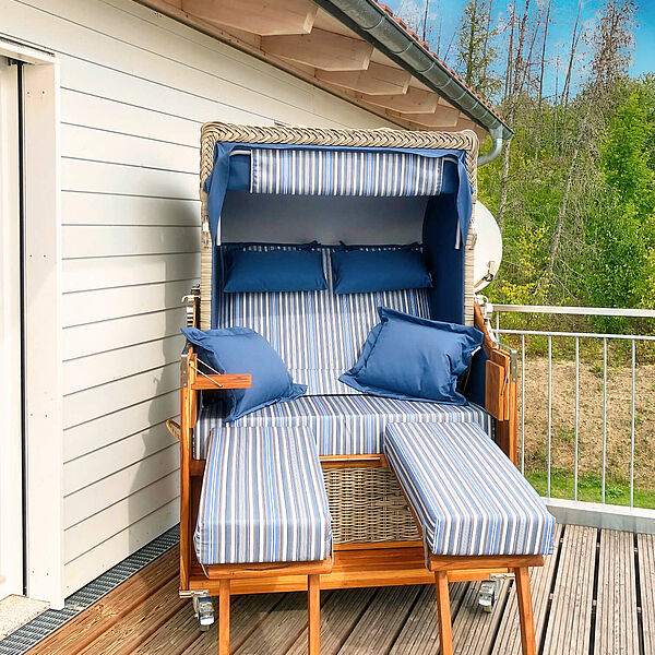 Strandkorb für zwei Personen auf dem Holzbalkon. 