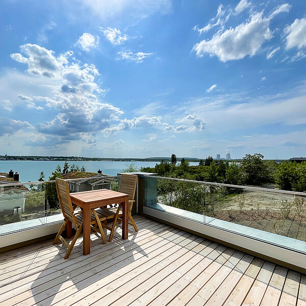 Sonnige Dach-Terrasse mit Blick ins Grüne und auf den See.