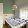 Schlaf-Zimmer mit Schrank, kommode, Fenster und Doppel-Bett aus Holz.