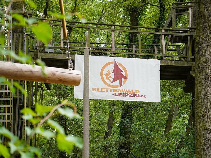 Banner des Kletterwald Leipzigs an einer Holzbrücke