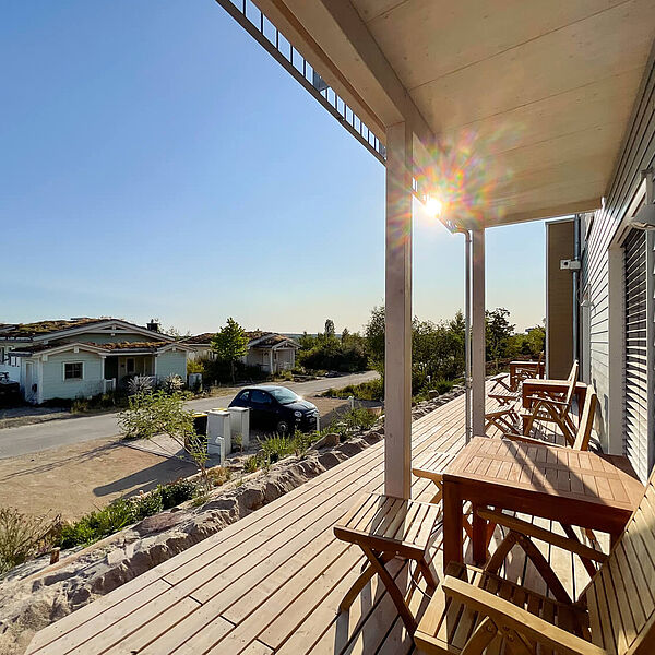 Bedachte Holz-Terrasse in der Sonne mit Blick auf den See.