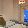 Schlafzimmer mit Doppelbett und bodentiefem Fenster.