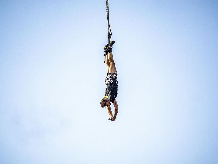 Mensch beim Bungee-Sprung mit Kamera in der Hand