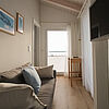 Couch mit Kissen im Wohnbereich. Rechts ein Fernseher an der Wand.