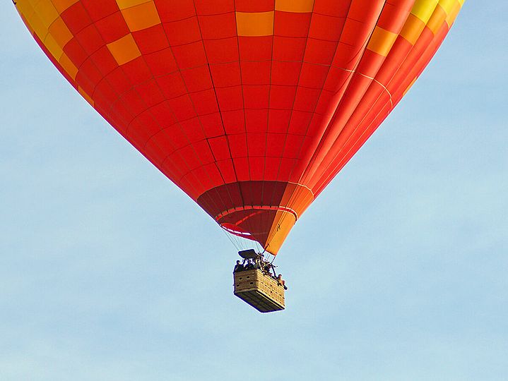 Korb eines roten Hießluftballons in der Luft