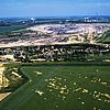 Farbige Luftaufnahme von Kahnsdorf neben grünen Feldern, direkt dahinter ein riesiges Erdloch vom Tagebau.