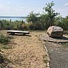 Gesteinsbrocken mit Gedenktafel, links daneben eine Bank mit Blick auf den dahinterliegenden Hainer See.