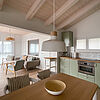 Helles Wohn-Zimmer: Ess-Tisch mit Holz-Schale und Blick aufs Sofa und die Küchen-Zeile.