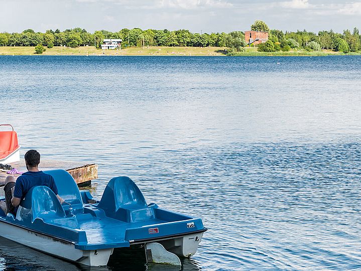 Tretbootverleih, im Hintergrund das Ufer der Tauchschule Delphin am Kulki