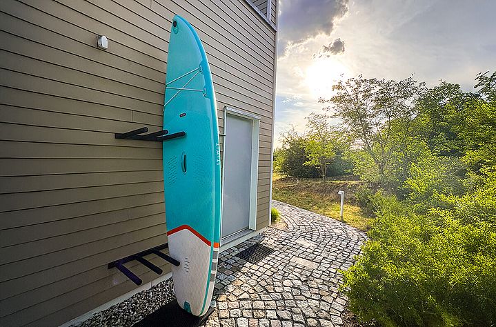 Blaues SUP-borard in einer SUP-Wandhalterung einsortiert. Das Board steht senkrecht.