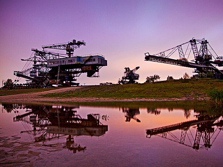 Braunkohle-Bagger im Abendrot spiegeln sich im See