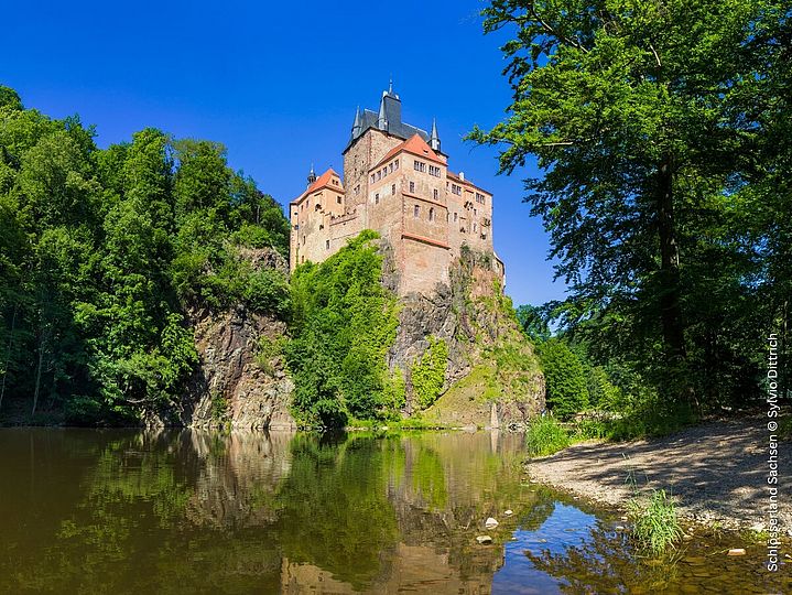 Burg auf Feld, Wald und Fluss direkt daneben