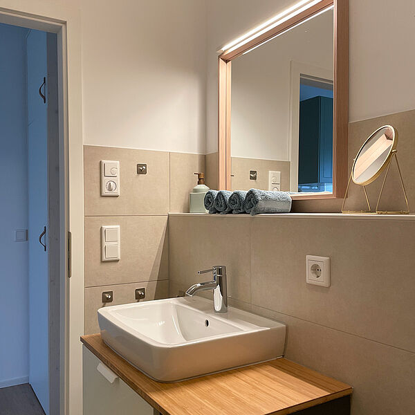 Wasch-Becken mit Spiegel, Tisch-Spiegel und Handtuch-Rollen.
