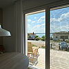 Blick auf die Holz-Terrasse und den dahinter liegenden See.