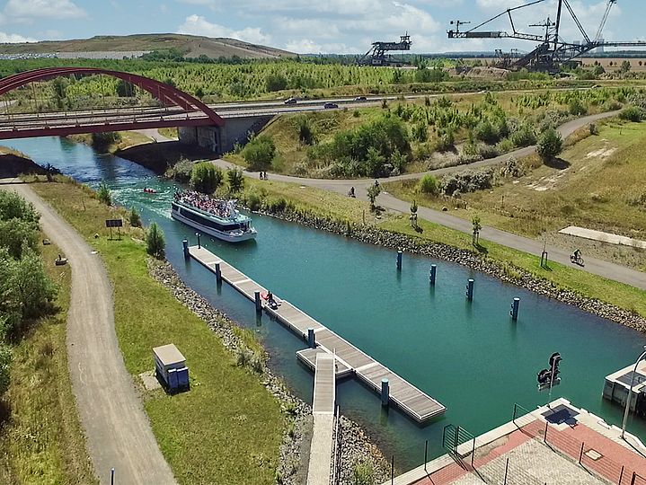 Personenschiff in Schleuse, im Hintergrund Braunkohlebagger des Bergbau-Technik-Parks