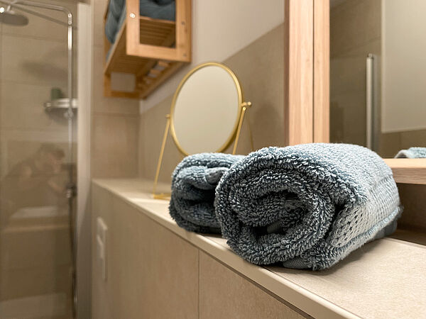 Bade-Zimmer: Zwei Handtücher vor einem Spiegel und ein Hand-Spiegel.