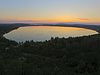 Vogelperspektive des kreisförmigen Runstedter Sees. Am Horizont ein Sonnenuntergang.
