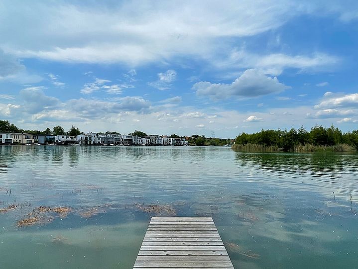 SHolzsteg ragt mittig in türkisblaues Wasser.