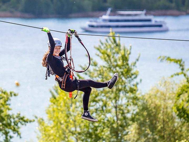 Mensch an Zipline, im Hintergrund Schiff auf dem Markkleeberger See
