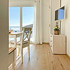 Wohnung 2: Wohnzimmer mit Esstisch, Kommode, Fernseher und traumhaftem Blick auf den Hainer See.