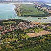 Luftaufnahme von Kahndsorf neben Feldern und Wald, dahinter direkt der blaue See.