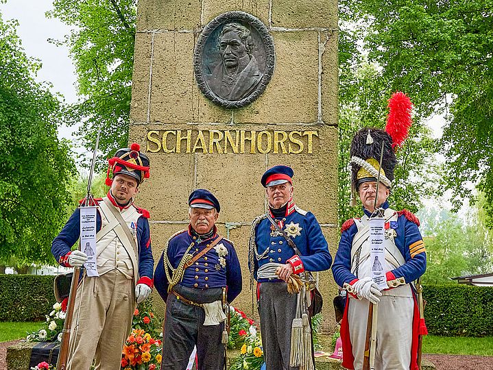 Vier Uniformierte posieren vor dem Denkmal zu Ehren von Gerhard von Scharnhorst.