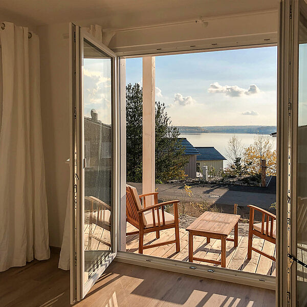 Wohnung 3: Traumhafter Blick durch die große geöffnete Fenstertür vom Wohnzimmer über die Terrasse auf den Hainer See.