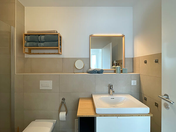Bad mit Keramik-Becken, Toilett, Spiegel und Regalbrett