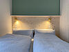 Doppelbett mit separaten Decken wird von 2 Bettlampen beleuchtet.