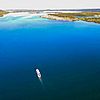 Vogelperspektive auf das blaue Wasser eines Sees, in der Mitte fährt ein Personenschiff. Am Rand des See sind Inseln zu erkennen.