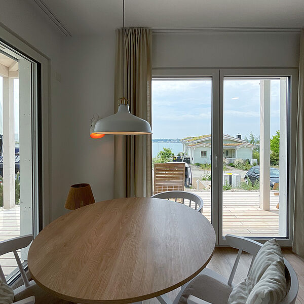 Runder Holz-Tisch mit 3 Stühlen und Blick auf den See.