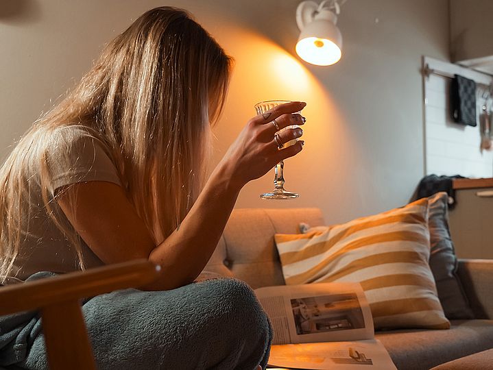 Frau sitzt auf Sofa mit einem Glas Wein, © Nicolas Anst