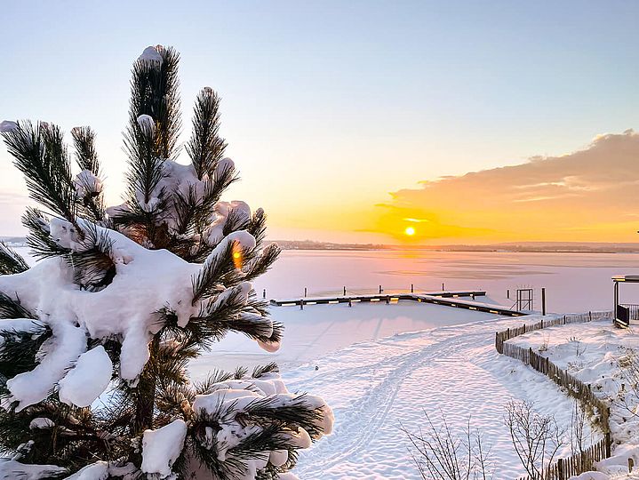 Sonnen-Untergang über dem schnee-bedeckten Hainer See.