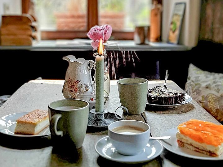 Gedeckter Bauernhaus-Tisch mit Kuchen, Kerze und Rose