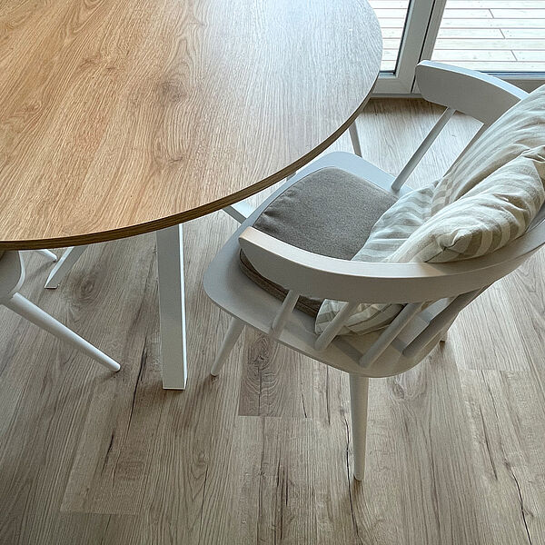 Runder Ess-Tisch mit weißem Holz-Stuhl.