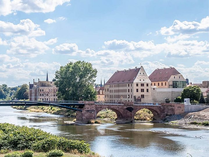 Eine Bogenbrücke führt über einen Fluss