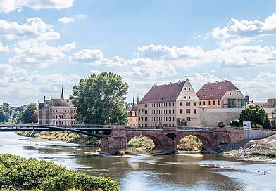 Eine Bogenbrücke führt über einen Fluss