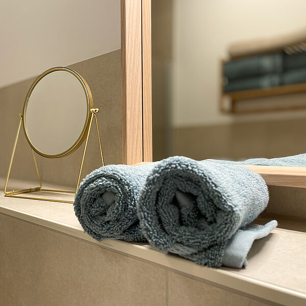 Bade-Zimmer: Zwei Handtücher vor einem Spiegel und ein Hand-Spiegel.
