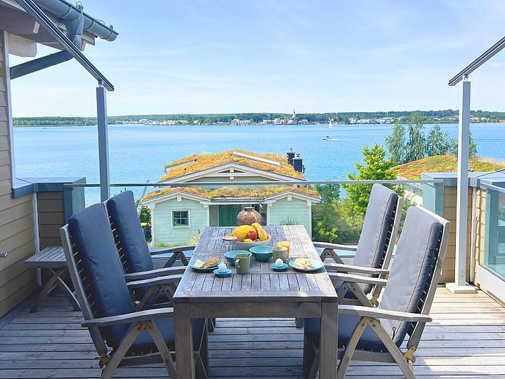 Gedeckter Tisch auf einer Dachterrasse. Im Hintergrund der Hainer See.