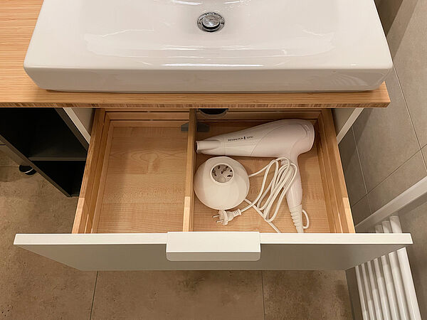 Ein Föhn liegt in der Schublade unter dem Wasch-Becken.