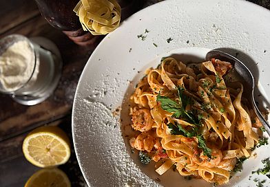 Tiefer Teller mit Tagliatelle, daneben eine aufgeschnittene Zitrone