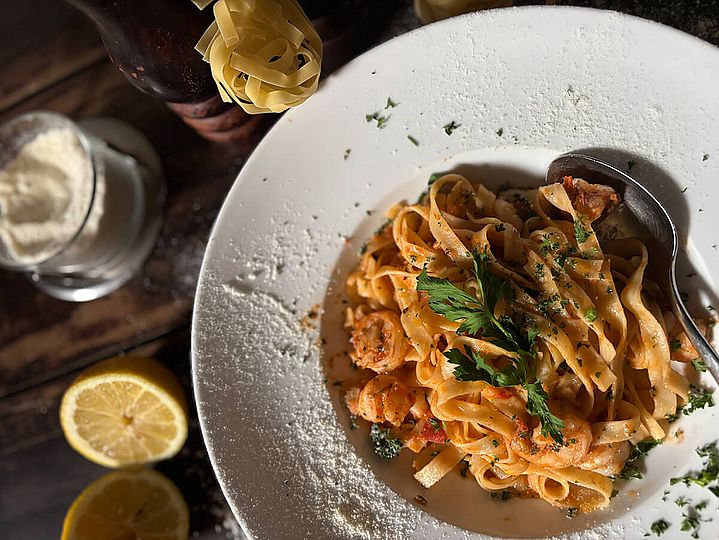 Tiefer Teller mit Tagliatelle, daneben eine aufgeschnittene Zitrone