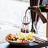 Eine Schüssel mit einen zubereitetem Essen und Gemüse, eine Hand füllt Wein in ein Weinglas daneben.