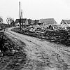 Schwarz-weiß-Foto von eine Straße, an den Ränden sieht man Schutthaufen, in der Ferne stehen noch ein paar Häuser