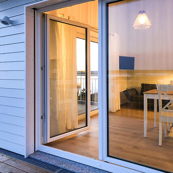 Blick von der Holzterrasse in das Wohnzimmer. Durch das Fenster Richtung Süden sieht man auf den Hainer See.
