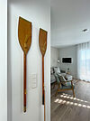 Garderobe aus Rudern. Dahinter ein Blick ins Wohnzimmer mit Sessel, Fernseherund Sofa.