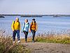 Drei Wanderer in Outdoorjacken, im Hintergrund der Schladitzer See