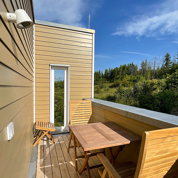 Sonniger Balkon mit Holz-Möbeln.