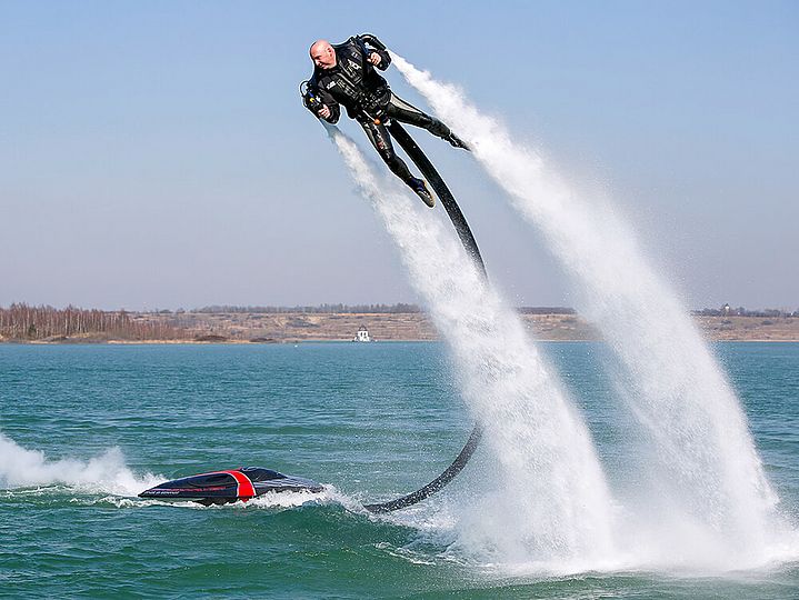 Ein Mensch mit einem Rucksack auf dem Rücken, der wie ein Raketenantrieb aussieht. Wasser wird durch einen Schlauch zum Rucksack gedrückt, der Rückstoß lässt den Menschen fliegen.